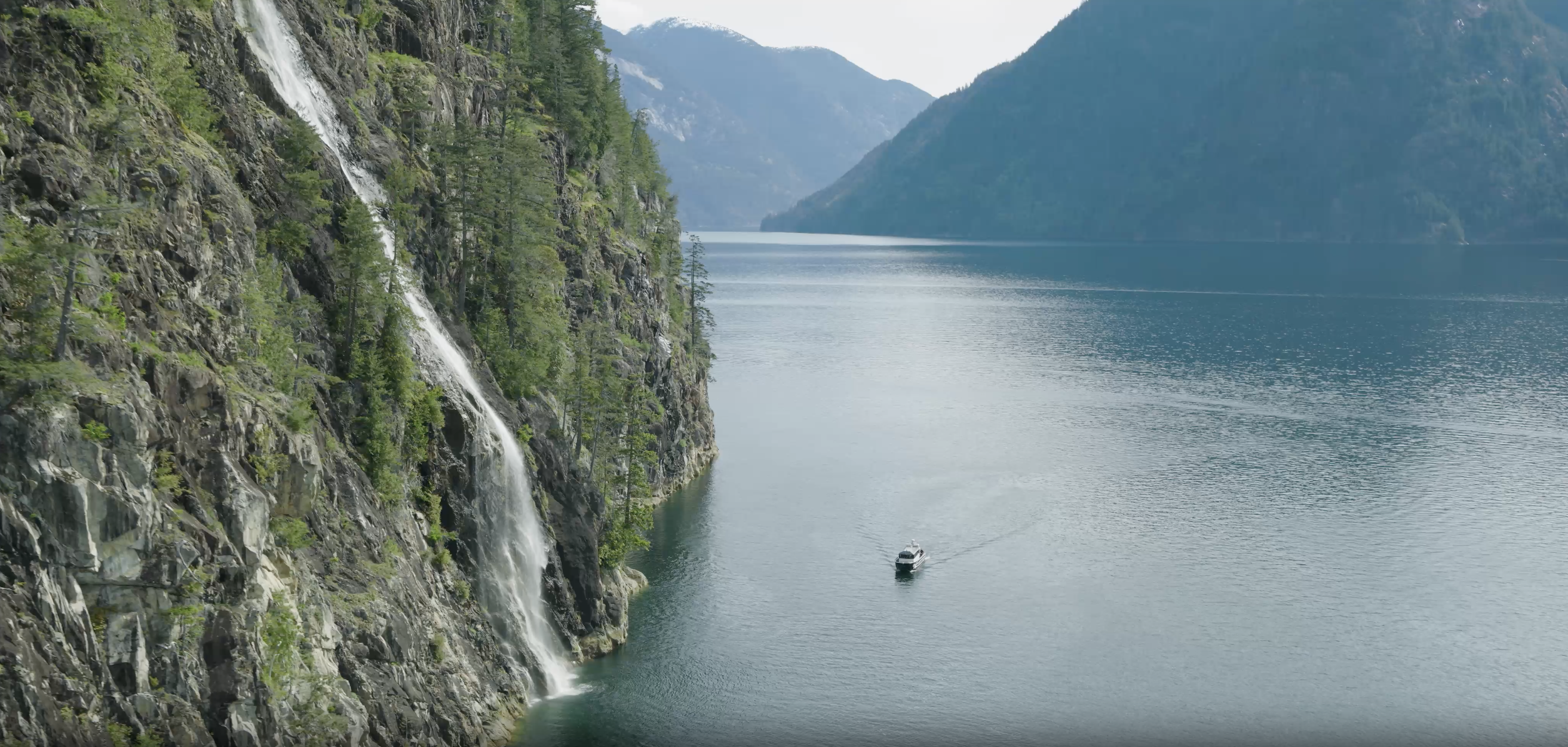 A boat coming around the side of a cliff in BC, Canada